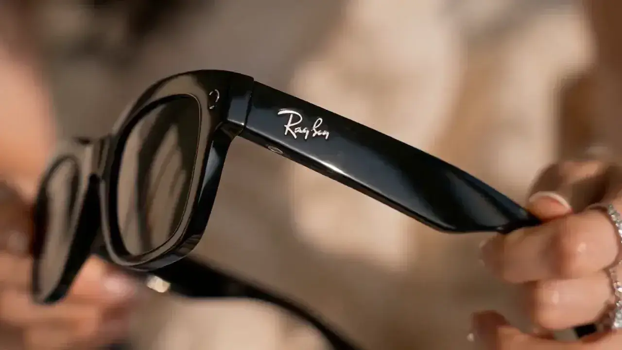 Hands lifting a pair of sunglasses out of the box, held up to the window light