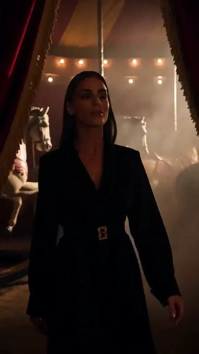 First frame: she walks through a dim circus backstage