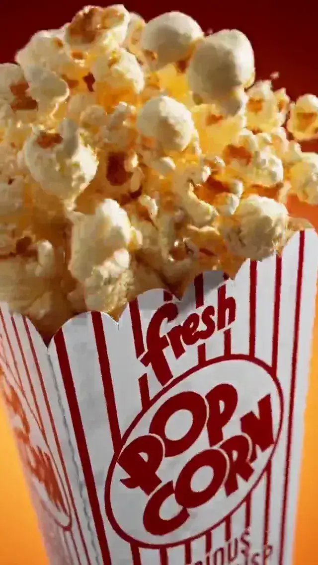 A striped cinema popcorn box on a red background in a fast-cut CGI commercial